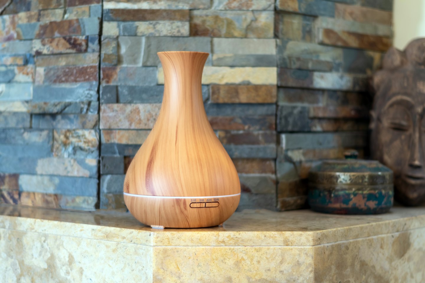 A vase shaped oil diffuser sits on a marble counter.